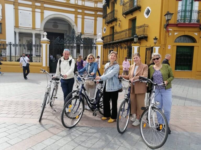 Lachende groep op de fietstour door Sevilla poseert bij de kleurrijke Macarena Basiliek met Nederlandse gids
